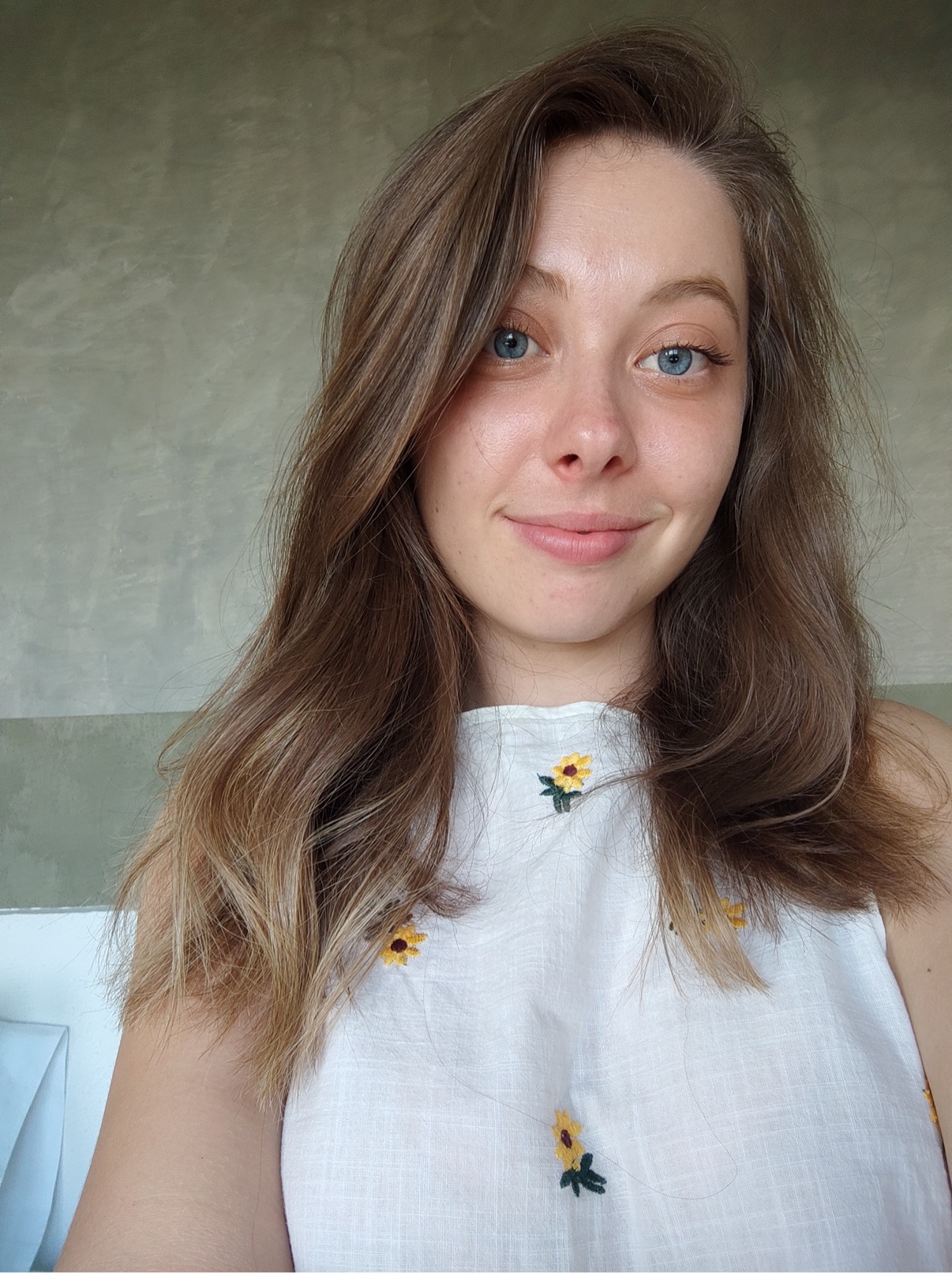 Yuliia in a white top with small sunflower embroidery